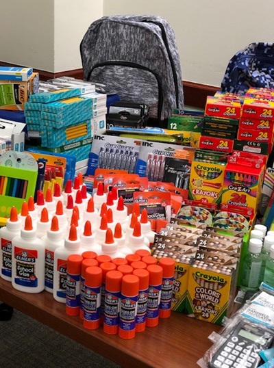 A table lined with rows and stacks of donated school supplies 